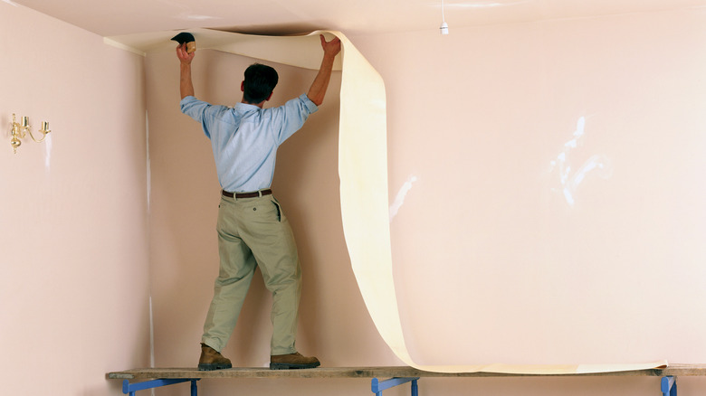 person applying wallpaper to ceiling