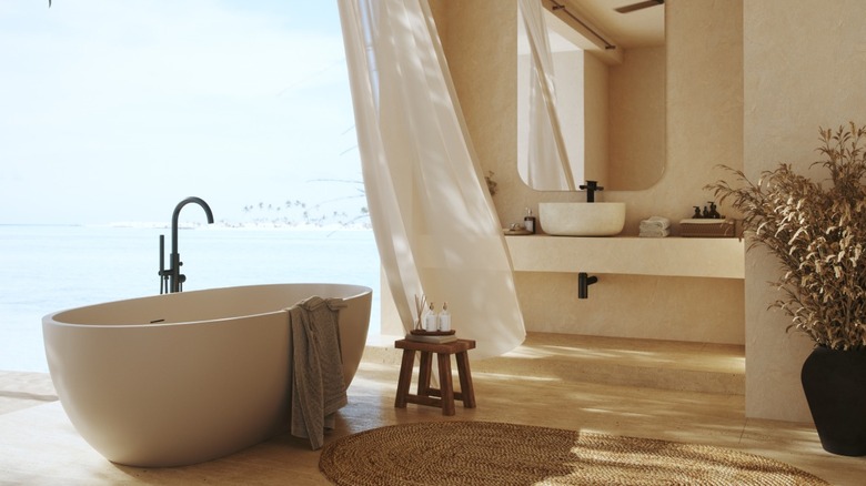 Warm, color-drenched beige bathroom with freestanding tub and open floor-to-ceiling window