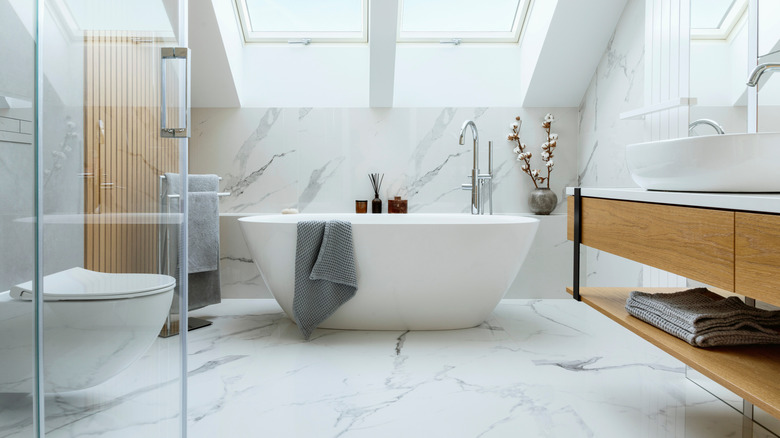 Modern bathroom with marble tiling and ceramic freestanding tub