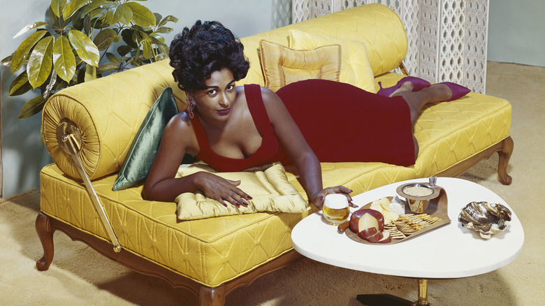 A woman lounges on a colorful sofa in the 60s