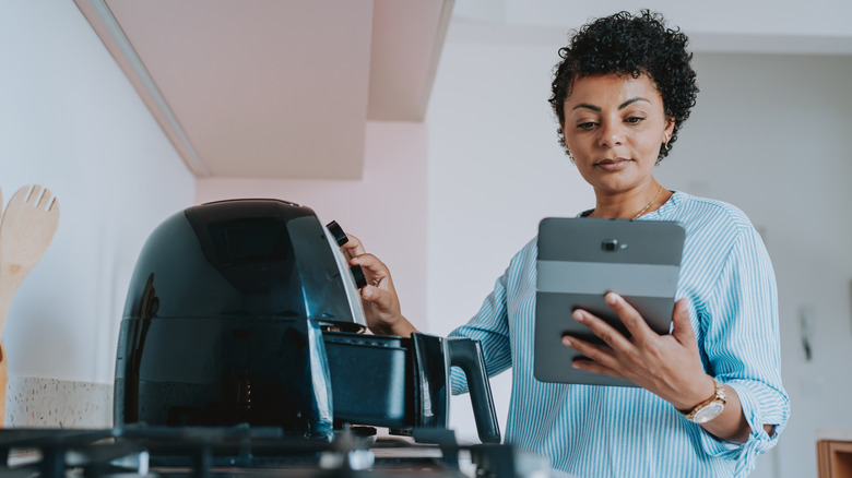 Woman programming an air fryer for cooking