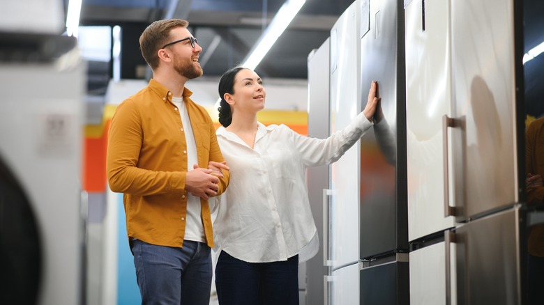 A man and a woman looking at refrigerators in store