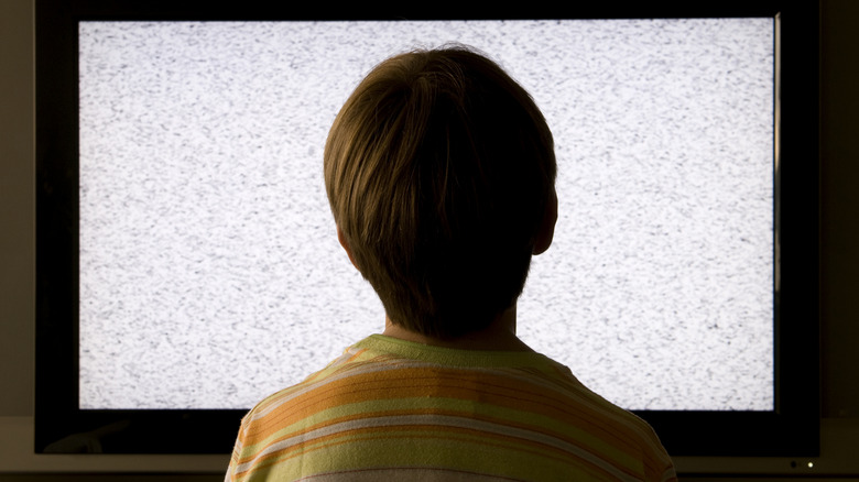 Person sitting in front of a broken television