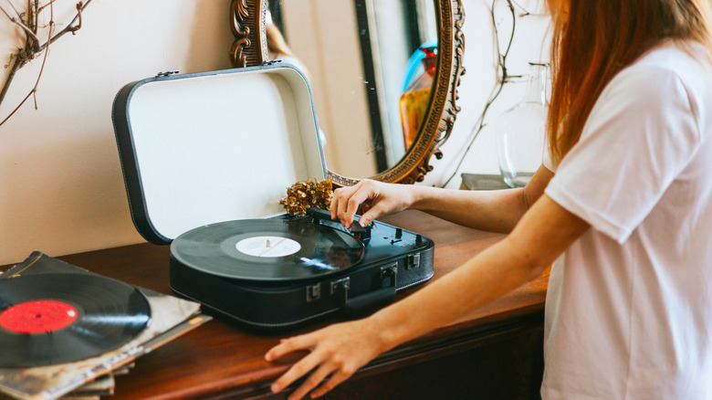 Girl positioning the arm of a turntable.