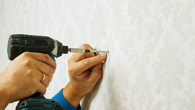 person drilling screw into wall