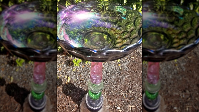 birdbath made from multicolored glassware with a pedestal made from glass vases