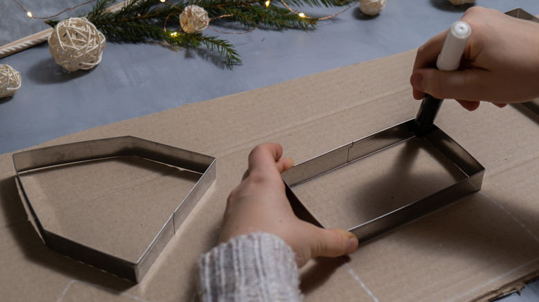 person tracing house shapes onto cardboard with white marker