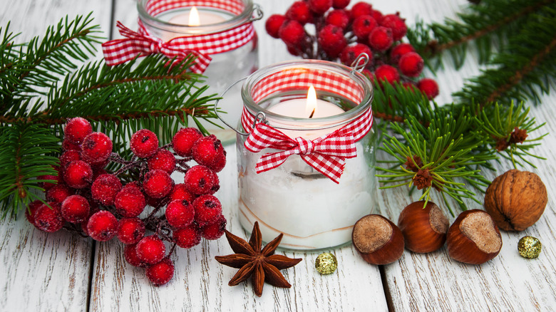 Mason jar candle luminary with a festive ribbon and decorative accents surrounding it