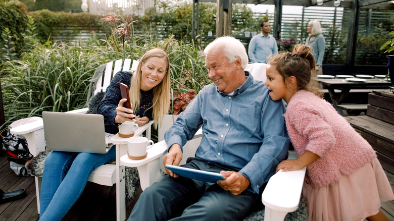 A family enjoying quality time in their backyard, each engaged with their devices while still sharing the space together.