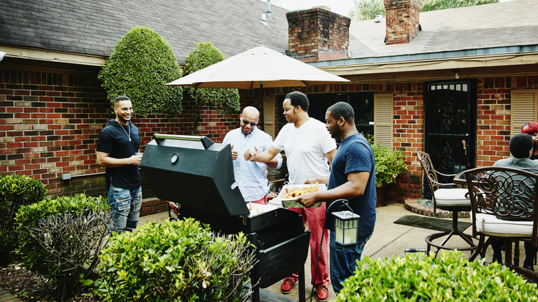 A group of young people having a barbecue party in a backyard