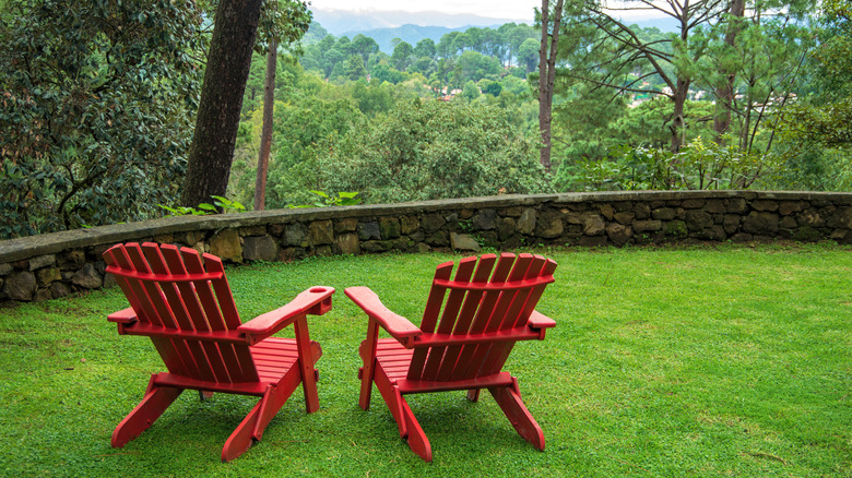 Red lawn chairs on backyard lawn.