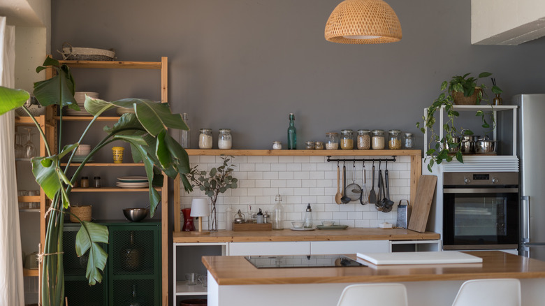 A kitchen with lots of open sehlving including one above the backsplash with jars of dry goods on it