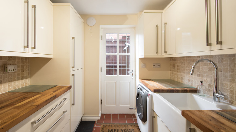 A laundry room with cabinets, a sink, and countertops.