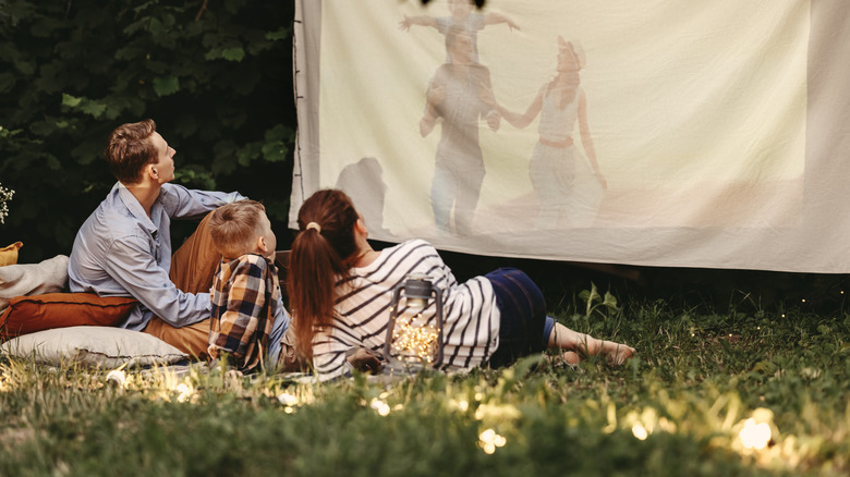 Fairy lights in the grass while family watches a movie