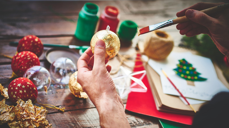 person painting Christmas ornaments with gold leaf