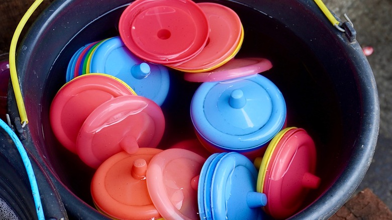 colorful plastic lids soaking in black bucket of water