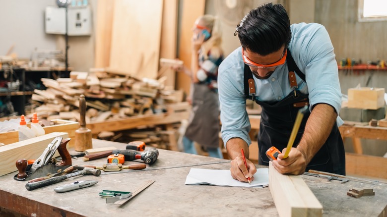 A carpenter measures a piece of wood.