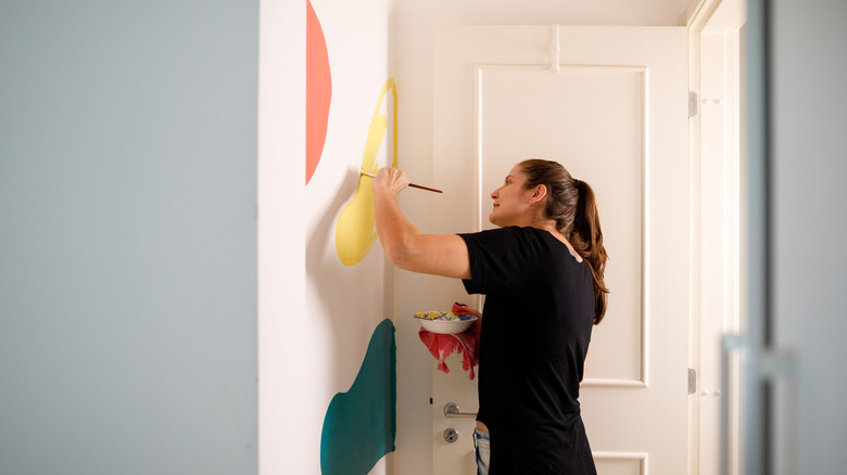 Woman painting abstract shapes on wall