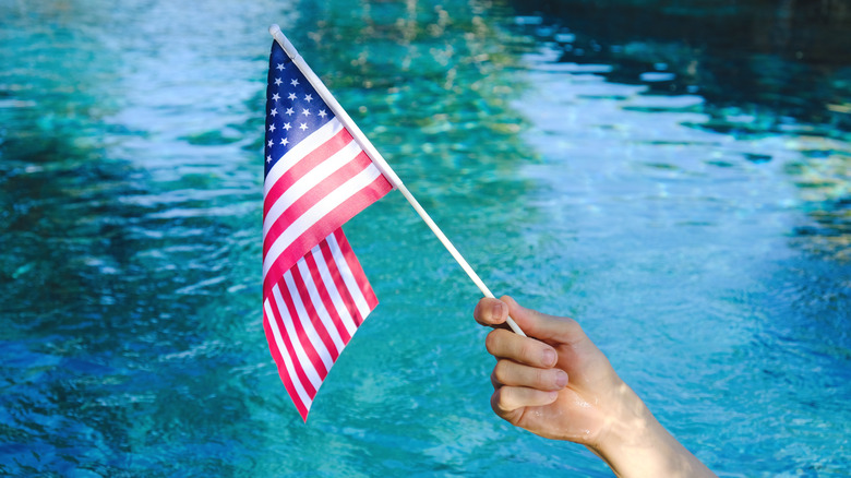 Hand waving american flag over water