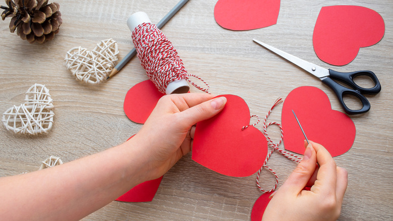 Hands making paper heart decorations