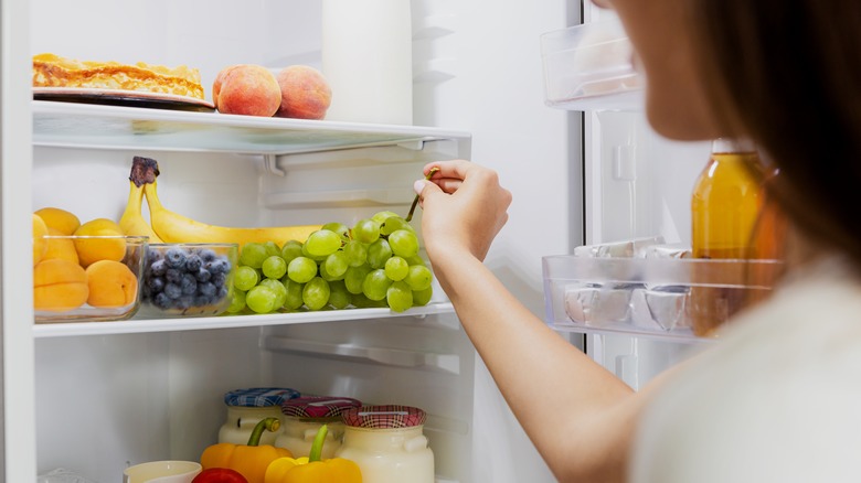 Woman grabs produce from fridge