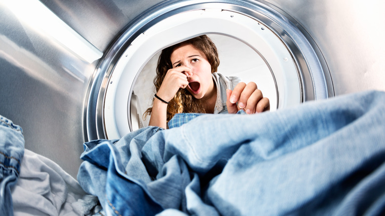 Woman holding nose doing laundry