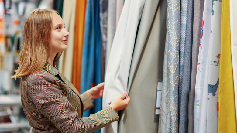 A woman smiling while choosing curtains.