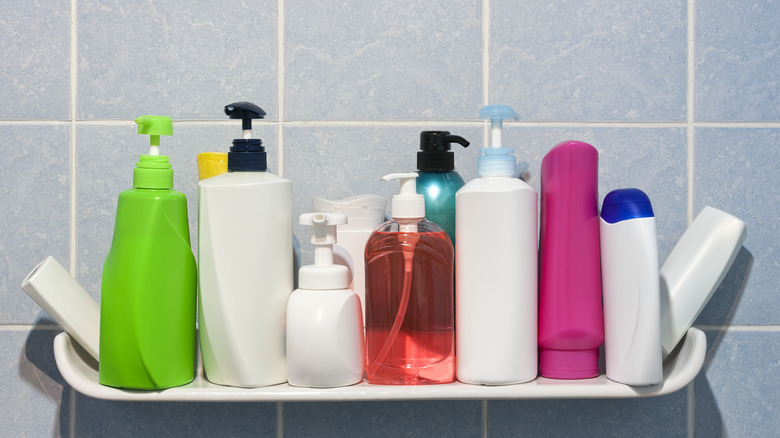 A bunch of different shampoo bottles sit on shower shelf.