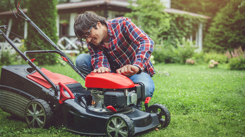 Man inspects his lawn mower outside