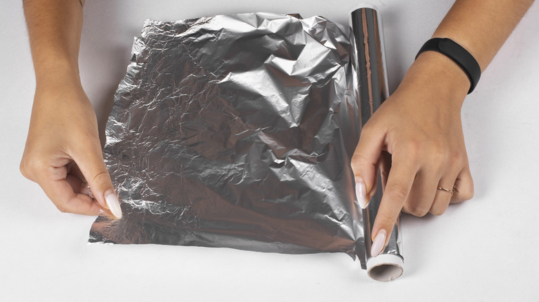 Woman tearing aluminum foil