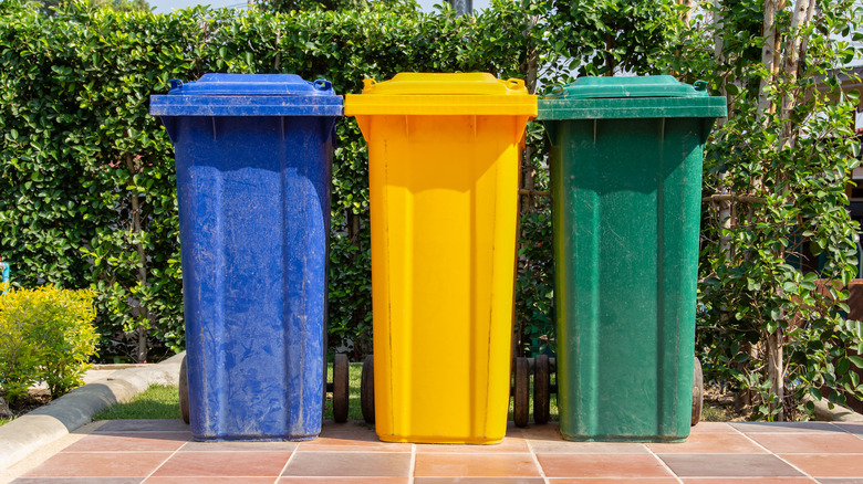 Three wheelie garbage bins lined up outside on tiled surface