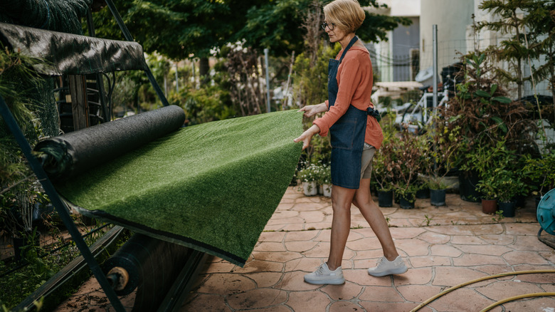 Woman pulling out artificial turf from roll.