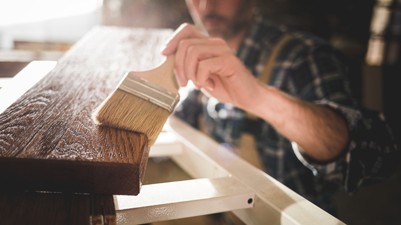 man staining wood board