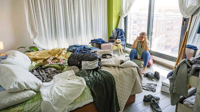 Woman sitting near window in messy room