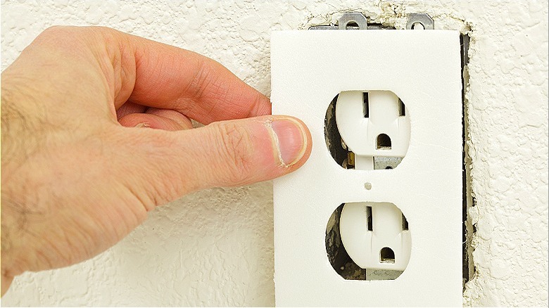 Hand pulling off outlet cover