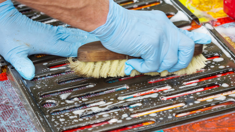 Someone scrubbing a grill grate