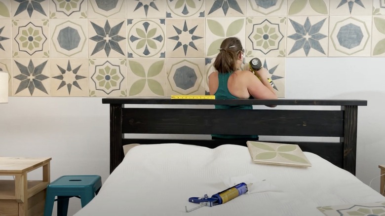 woman gluing wood tiles to wall