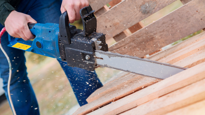 Person chainsawing wood pallet