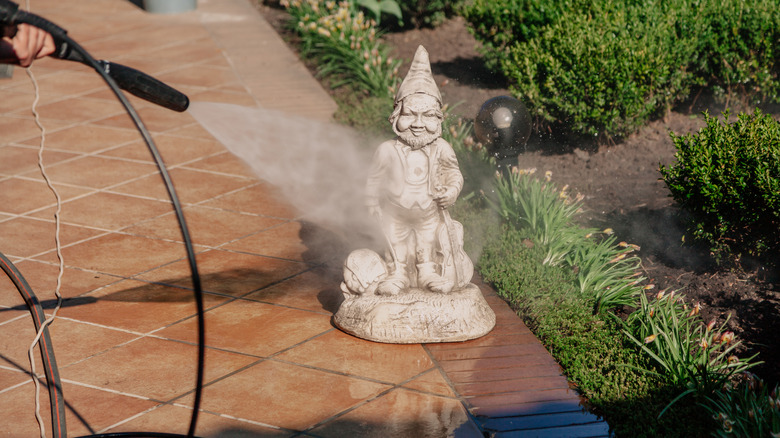 A pressure washer cleans a garden statue