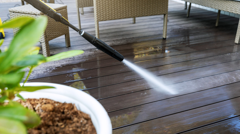 A pressure washer cleans a wooden deck