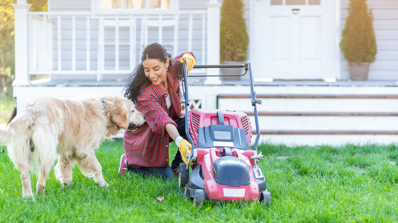 Woman adjusting mower with dog