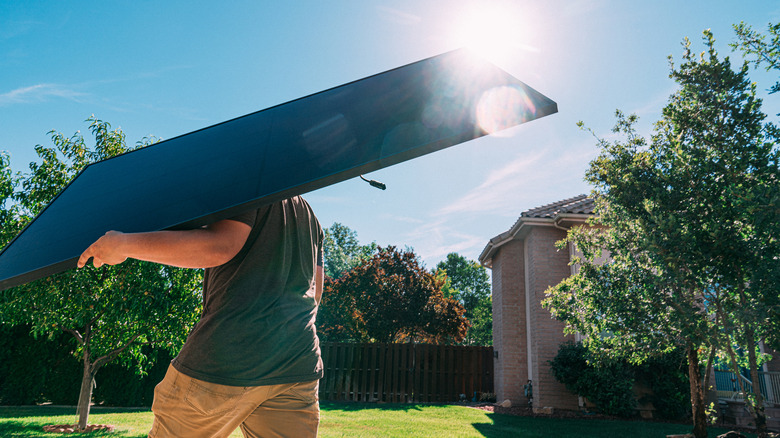 man carrying solar panel outside