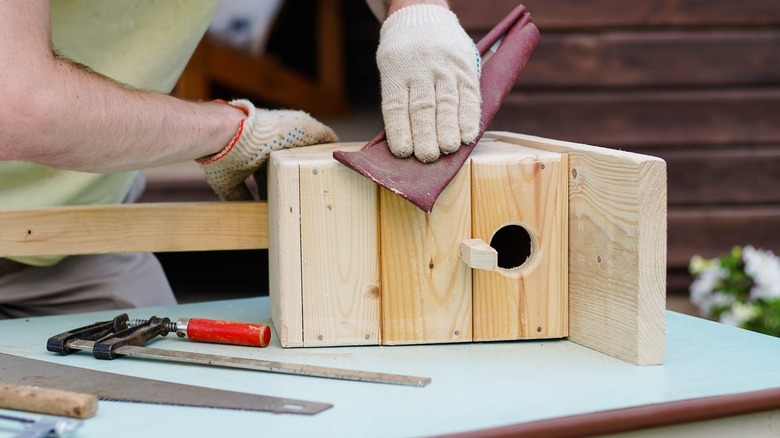 Sanding wooden birdhouse 