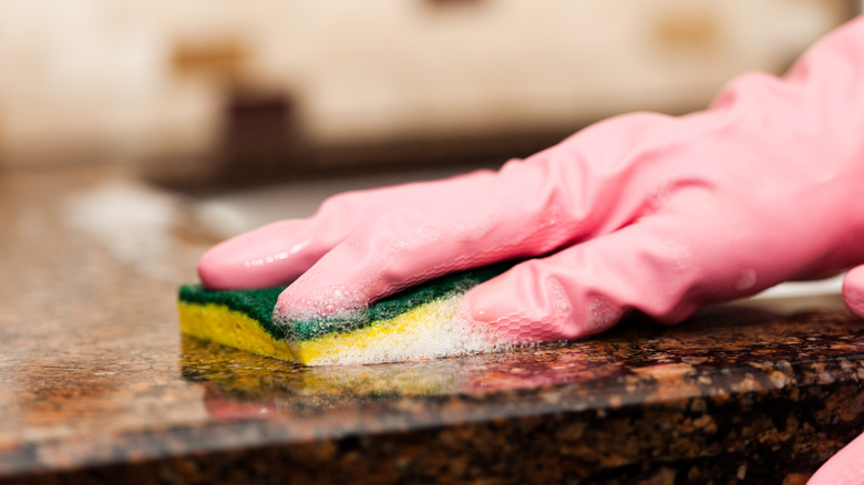 wiping granite with soapy sponge