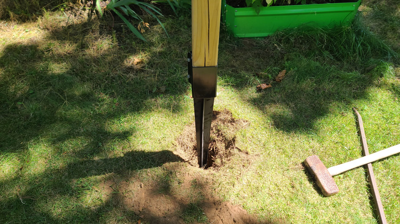 Fence post with metal anchor being installed