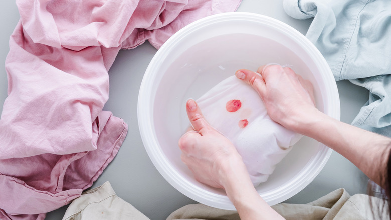 person soaking blood-stained fabric