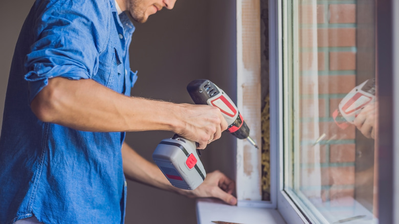 Man installs window with drill