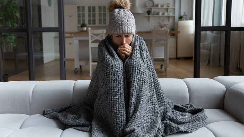 Woman cold indoors wearing blanket