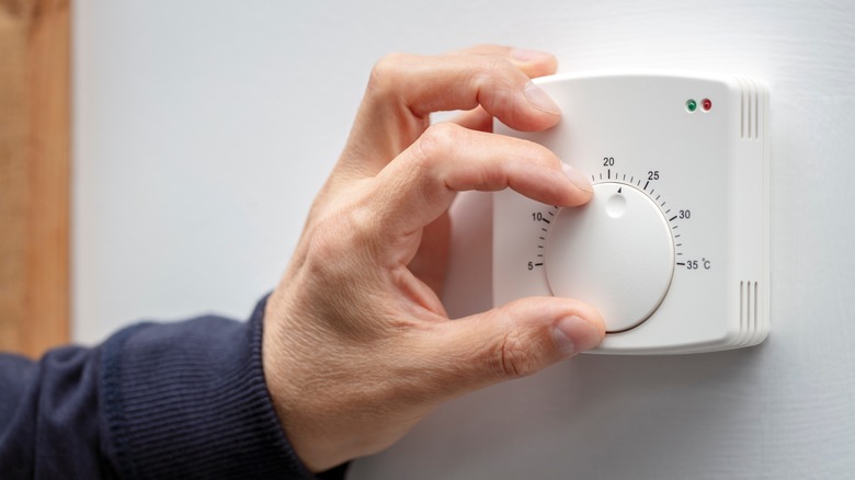 Hand adjusting the thermostat