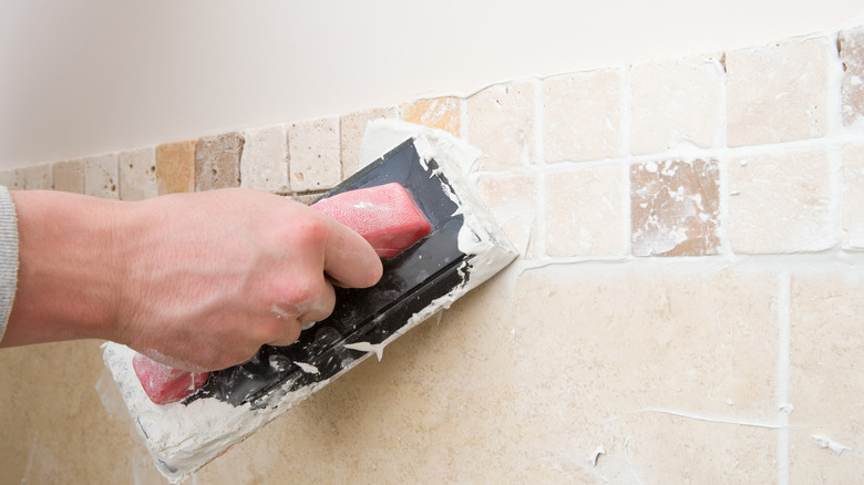 Person applying grout to stone tile border